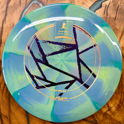 A disc golf disc from MVP Disc Sports featuring a blue and green swirled pattern with a black geometric star design and gold foil accents, displayed on a wooden surface.