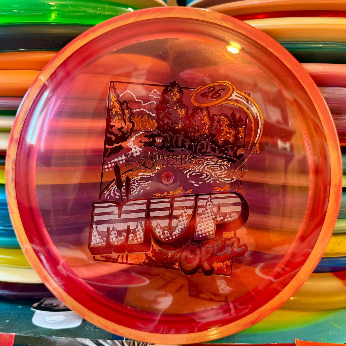 Axiom Discs Proton Bokeh fairway driver, translucent red orange with an MVP Open 2026 stamp, top view